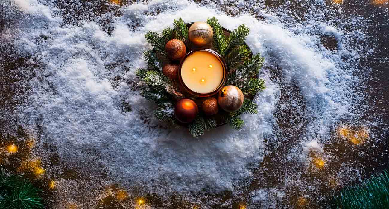 Cosy christmas candle by The Plant Workshop with snow and christmas tree branches.